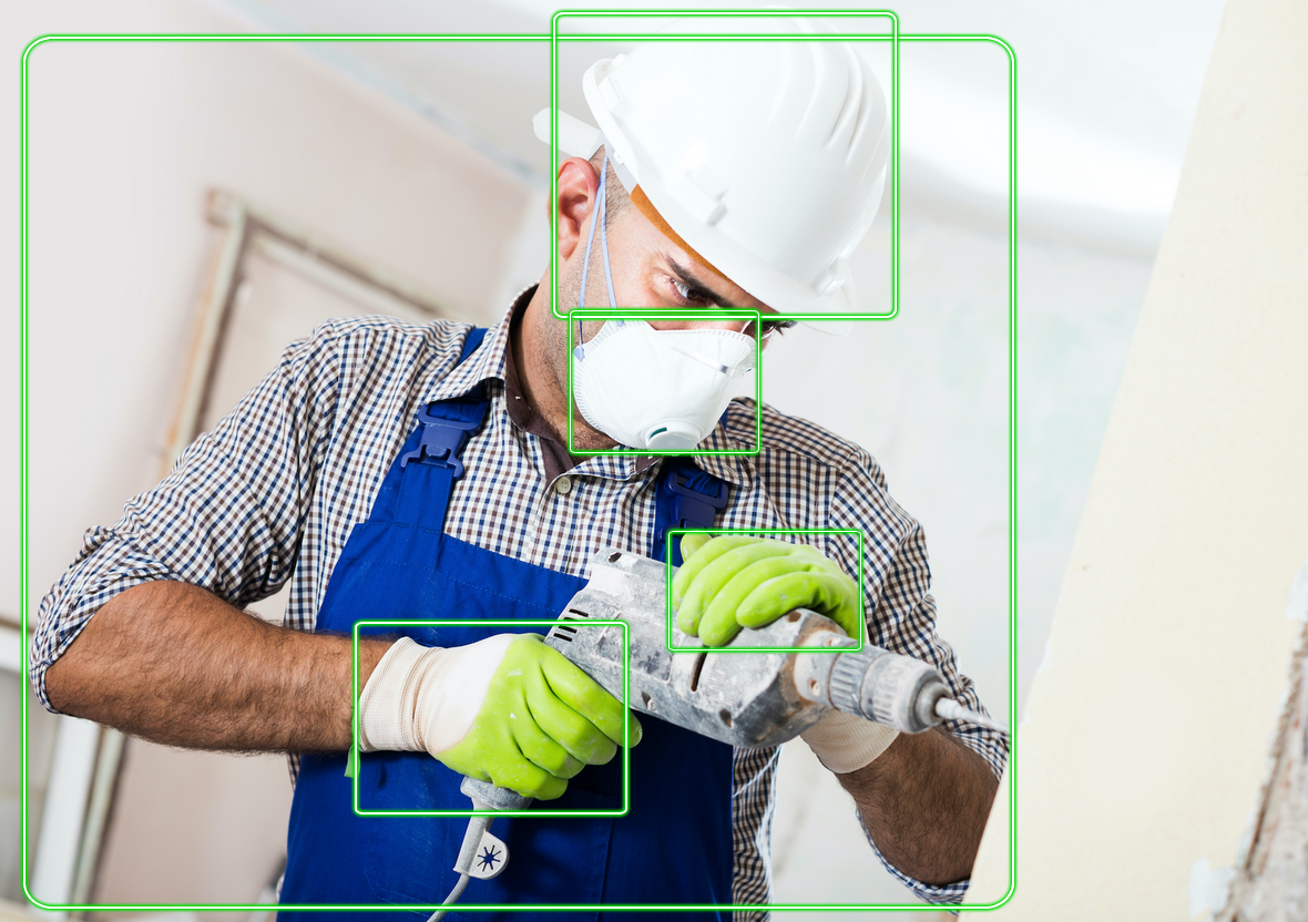 Bauarbeiter mit kariertem Hemd, Schutzhelm und Gesichtsmaske, hält ein Elektrowerkzeug in der Hand. In grünen Kästchen sind Gesicht, Schutzhelm, behandschuhte Hand und Werkzeug hervorgehoben.