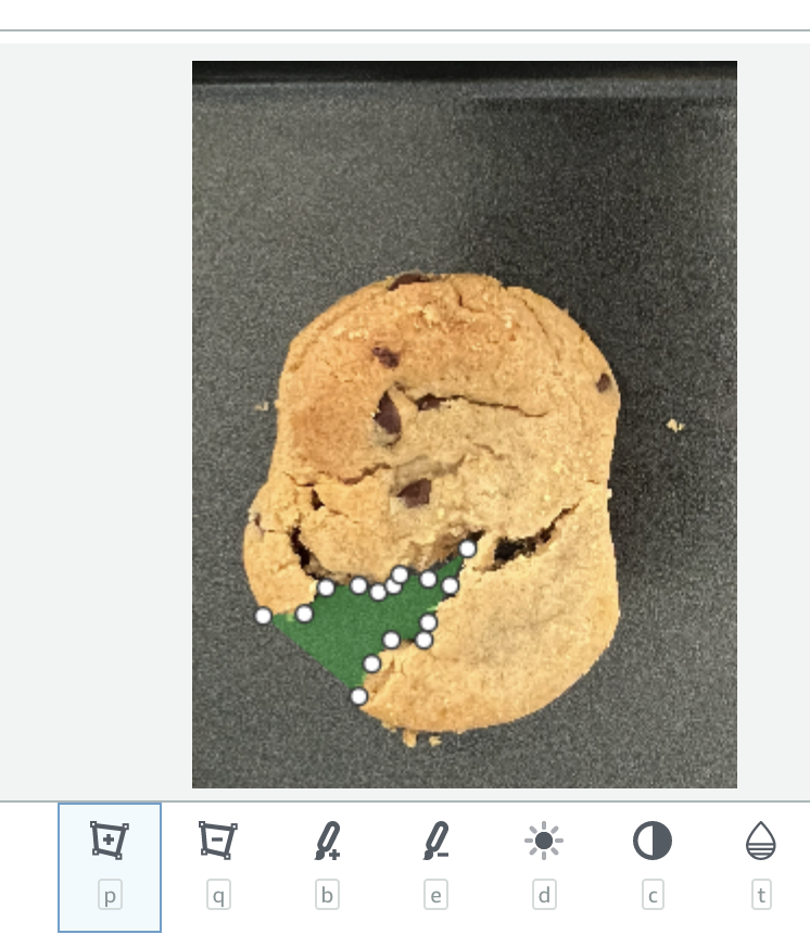 Chocolate chip cookie with a green shape and white dots arranged in a pattern.