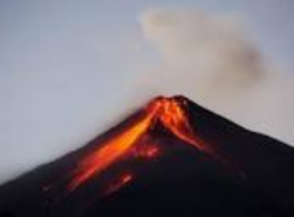 Vulcão em erupção com lava derretida escorrendo pelas laterais em contraste com um céu nublado.