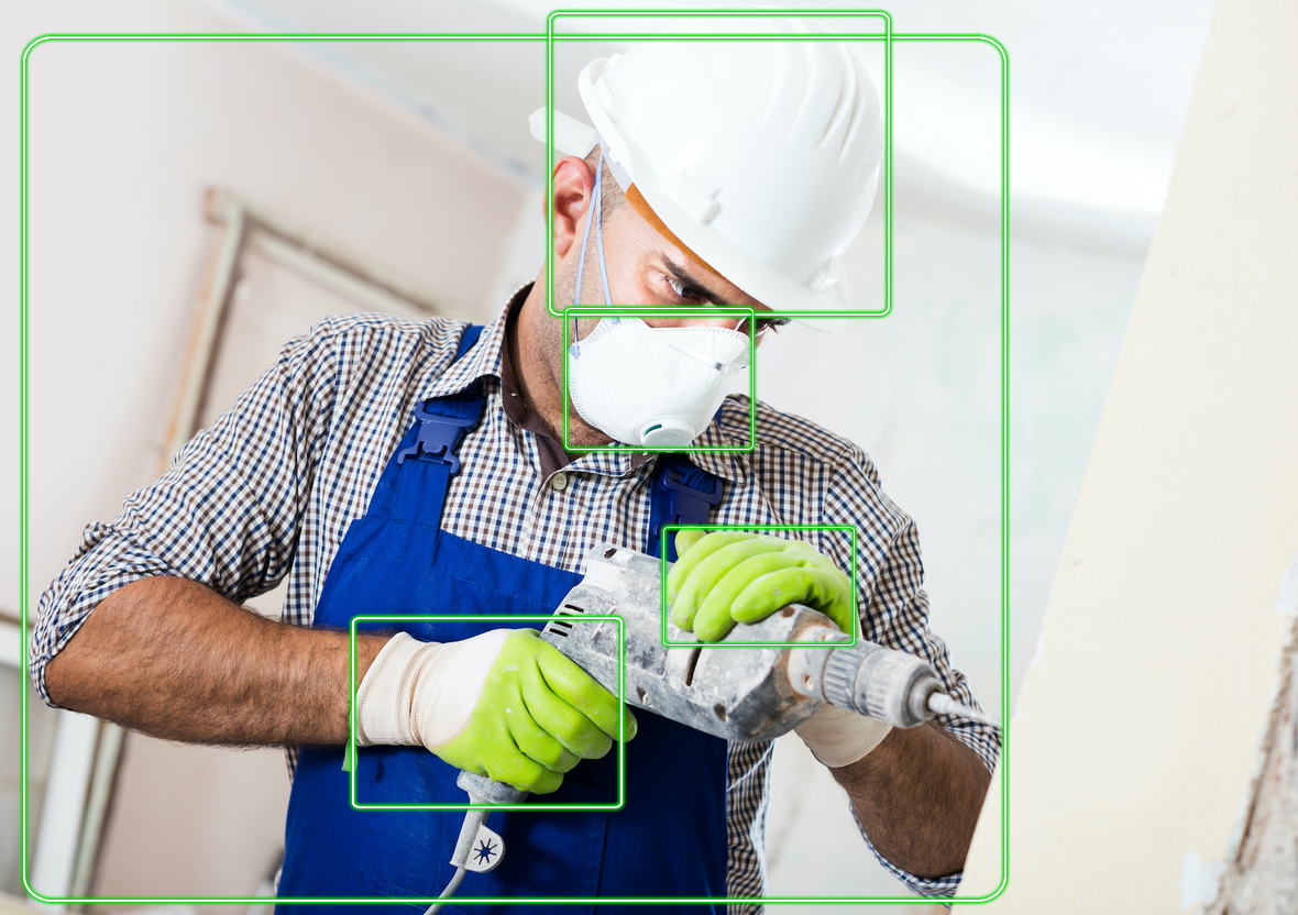 Trabalhador da construção civil vestindo camisa quadriculada, capacete e máscara facial segurando uma ferramenta elétrica. As caixas verdes destacam o rosto, o capacete, a mão enluvada e a ferramenta.